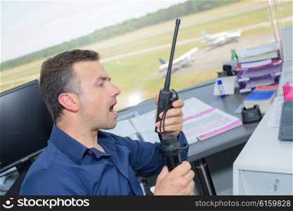Man in control tower shouting into radio receiver