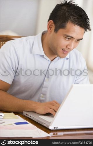 Man in dining room using laptop