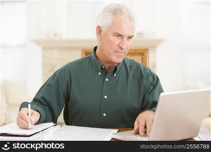 Man in dining room with laptop and paperwork