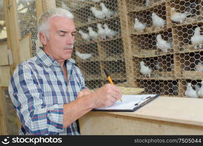 Man in dovecote writing on clipboard