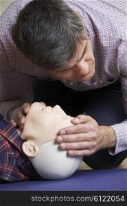 Man In First Aid Class Checking Airway On CPR Dummy
