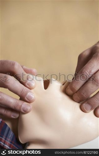Man In First Aid Class Performing Mouth To Mouth Resuscitation On Dummy