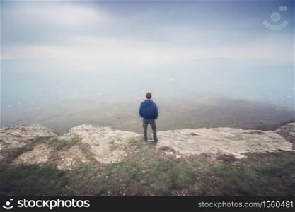 Man in fog in mountain looking to infinity. Conceptual scene.
