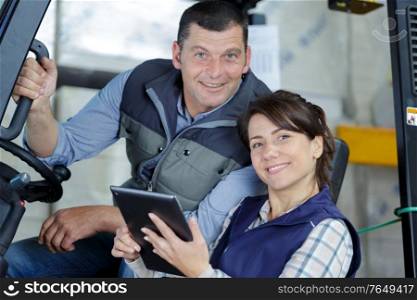 man in forklift talking to woman in white jacket