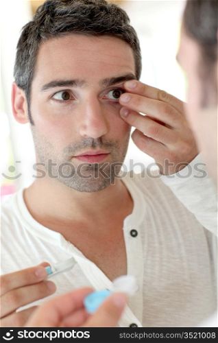 Man in front of mirrror putting ocular lens