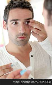 Man in front of mirrror putting ocular lens