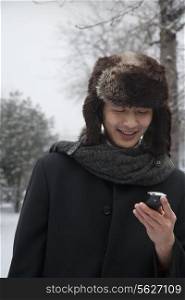 Man in Fur Hat Looking at Cell Phone