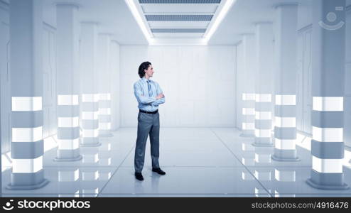 Man in futuristic interior. Confident businessman with arms crossed on chest in virtual tunnel room