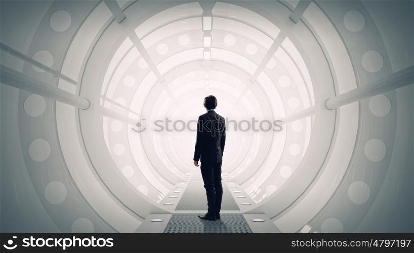 Man in futuristic interior. Mixed media. Businessman standing with back in futuristic designed 3D room