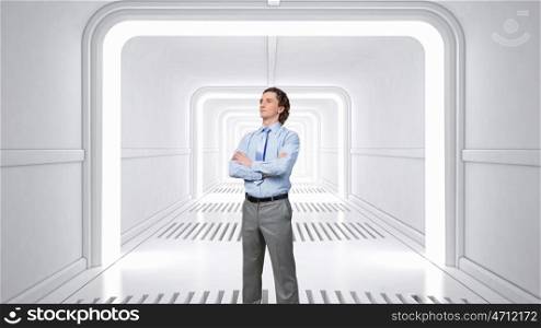 Man in futuristic interior mixed media. Young confident businessman with arms crossed on chest in virtual room