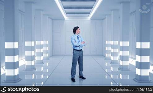 Man in futuristic interior mixed media. Young confident businessman with arms crossed on chest in virtual room