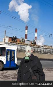 Man in gas mask on background of city of landscape with pipes and smoke