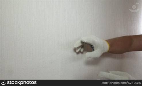 Man in glove showing how to remove old wallpaper