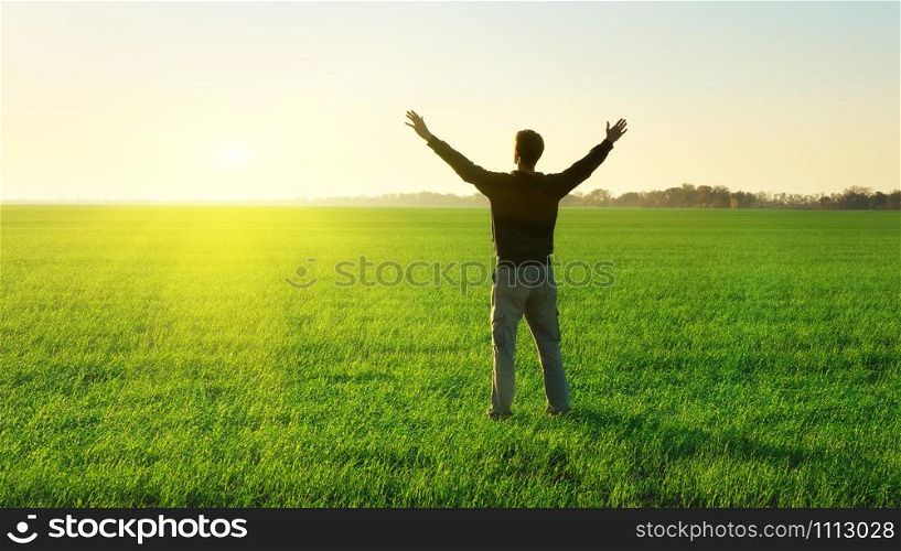 Man in green meadow raise hands up. Emotional scene.
