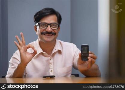 Man in happy mood while blood sugar level is showing normal on Glucometer
