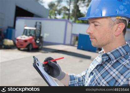 Man in hardhat making notes on clipboard