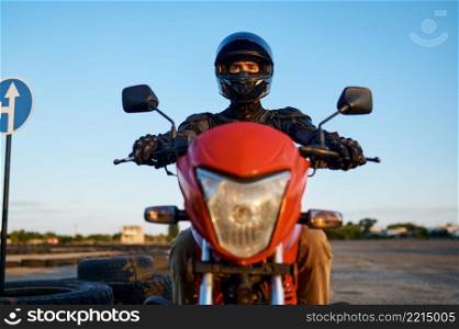 Man in helmet on motorbike, front view, lesson in motorcycle school. Training of motorcyclists beginners, biker practicing on motordrome in motorschool. Man on motorbike, front view, motorcycle school