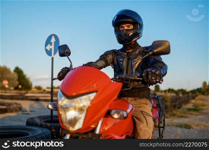 Man in helmet on motorbike, front view, lesson in motorcycle school. Training of motorcyclists beginners, biker practicing on motordrome in motorschool. Man on motorbike, front view, motorcycle school