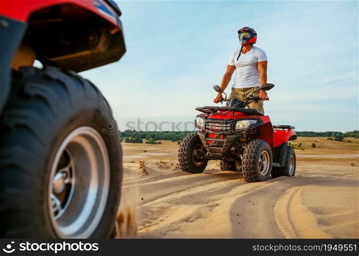 Man in helmet rides on atv in desert sands. Male person on quad bike, sandy race, dune safari in hot sunny day, 4x4 extreme adventure, quad-biking. Man in helmet rides on atv in desert sands