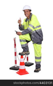 Man in high visibility overalls with a traffic cone and barrier