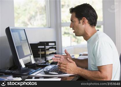 Man in home office using computer looking frustrated