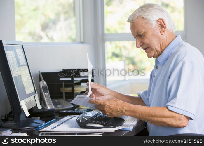 Man in home office with paperwork and computer