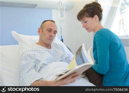 man in hospital with visitor reading a brochure