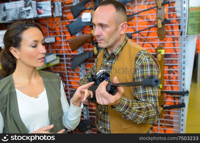 Man in hunting shop looking at rifle