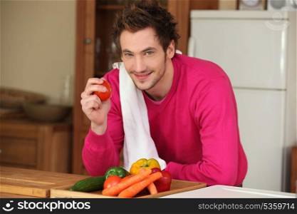 Man in kitchen holding tomato