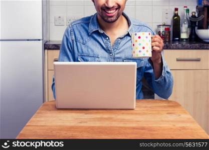 Man in kitchen is working on laptop