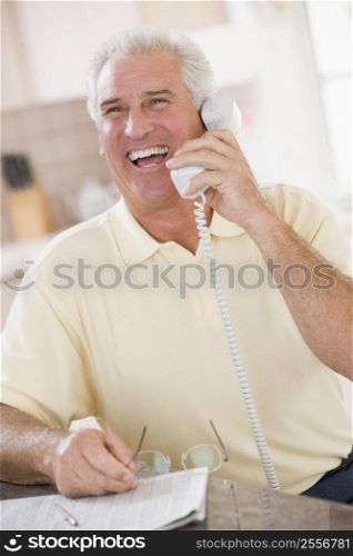 Man in kitchen on telephone laughing