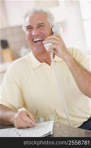 Man in kitchen on telephone laughing