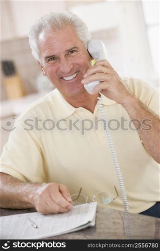 Man in kitchen on telephone smiling