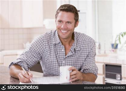 Man in kitchen reading newspaper and smiling