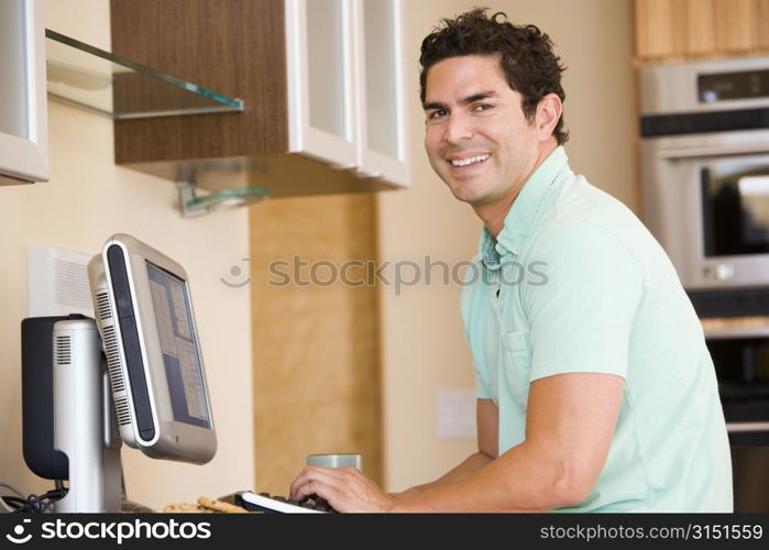 Man in kitchen using computer and smiling