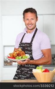 Man in kitchen with apron cooking chicken