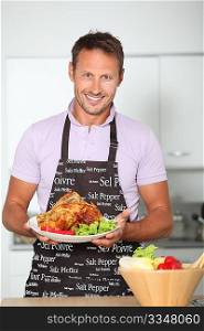 Man in kitchen with apron cooking chicken