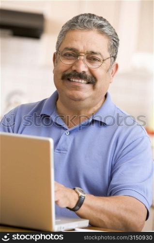 Man in kitchen with laptop smiling
