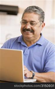 Man in kitchen with laptop smiling