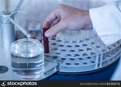 Man in laboratory, holding tube of liquid, close-up