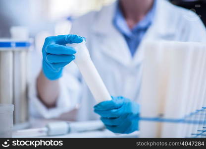 Man in laboratory, wearing protective gloves, holding test tube