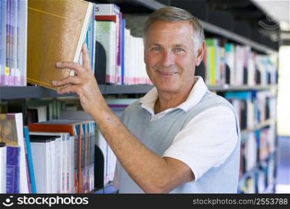 Man in library pulling book off a shelf (depth of field)