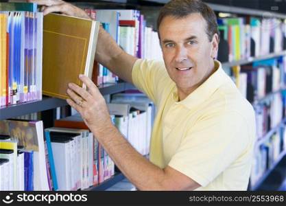 Man in library pulling book off a shelf (depth of field)