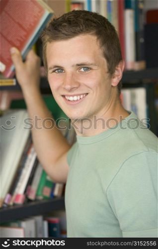 Man in library pulling book off shelf (selective focus)