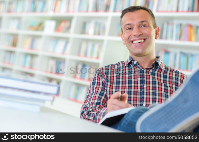 Man in library with feet on table