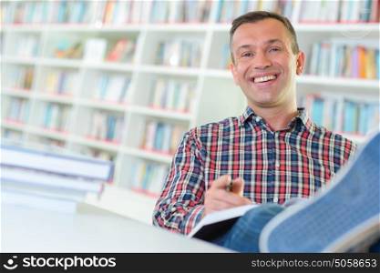 Man in library with feet on table