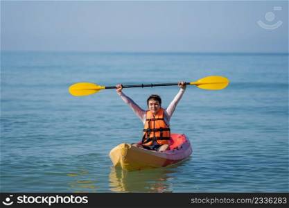man in life jacket paddling a kayak boat in the sea