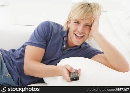 Man in living room holding remote control laughing