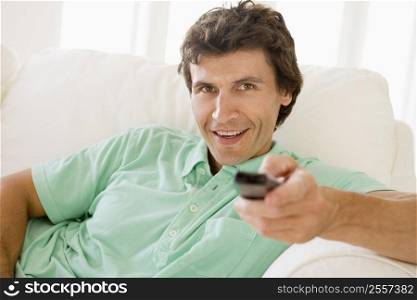 Man in living room holding remote control smiling
