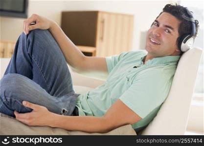 Man in living room listening to headphones smiling